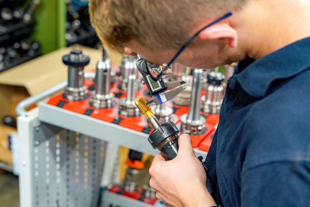 A worker in a tool warehouse inspects and selects cutters for work on a CNC milling and turning machine.